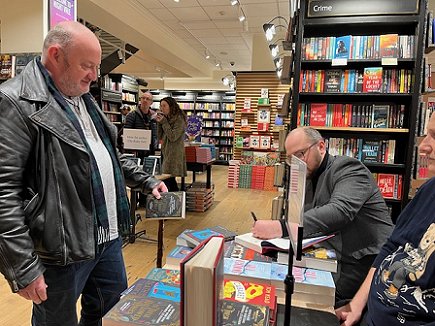 Tom Mead signing a book for a customer