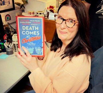 photograph of a smiling Samantha Hayes holding up a copy of Death Comes at Christmas, edited by Marie O'Regan and Paul Kane