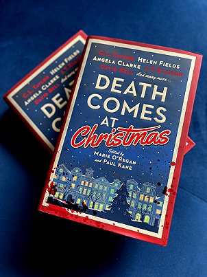 photograph showing two copies of Death Comes at Christmas, edited by Marie O'Regan and Paul Kane, lying on a blue cloth-covered surface