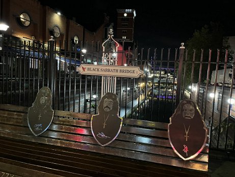 image of the Black Sabbath bridge at night, showing a bench with images of three of the band members