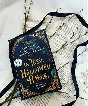 Image showing a copy of In These Hallowed Halls, edited by Marie O'Regan and Paul Kane, lying on scattered typed pages, willow branches and a black ribbon