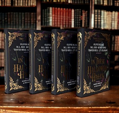 Image showing four standing copies of In These Hallowed Halls, edited by Marie O'Regan and Paul Kane, on a wooden surface in front of full bookshelves