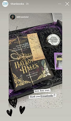 screenshot showing a black box lined with purple and black tissue paper, containing a tied copy of In These Hallowed Halls, edited by Marie O'Regan and Paul Kane, and a bookmark, teabag and In These Hallowed Halls candle