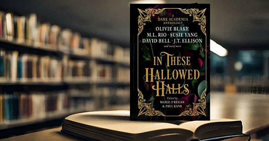 photograph showing a standing copy of In These Hallowed Halls, edited by Marie O'Regan and Paul Kane, on top of an open book on a wooden surface. In the background is a wall lined with filled bookshelves