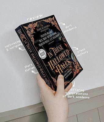 a hand holding a proof copy of In These Hallowed Halls, edited by Marie O'Regan and Paul Kane. Text reads review - dark academia, captivating and intriguing, short stories, great authors, differing interpretations of dark academia