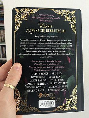 photograph of a man's hand holding up a copy of the Polish edition of In These Hallowed Halls, edited by Marie O'Regan and Paul Kane, to show the back cover