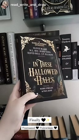 a woman's hand holds a copy of In These Hallowed Halls, edited by Marie O'Regan, up in front of a bookshelf. Text reads Finally