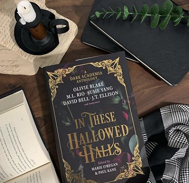 photograph of a woman with long brown hair wearing a black slip and brown cardigan, holding a copy of In These Hallowed Halls, edited by Marie O'Regan and Paul Kane