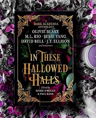 Image showing a copy of In These Hallowed Halls, edited by Marie O'Regan and Paul Kane, lying on a purple and grey floral background, with a purple candle and white feather alongside