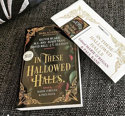 Image of a copy of In These Hallowed Halls, edited by Marie O'Regan and Paul Kane, lying on a dark cloth alongside the press release