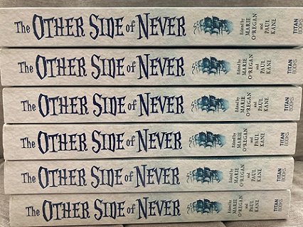 stack of six copies of The Other Side of Never, edited by Marie O'Regan and Paul Kane, showing the books' spines