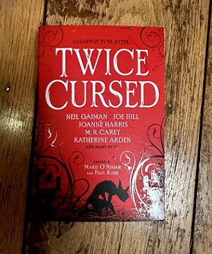 copy of Twice Cursed, edited by Marie O'Regan and Paul Kane, on a wooden surface