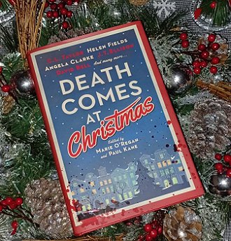 photograph of a copy of Death Comes at Christmas, edited by Marie O'Regan and Paul Kane, lying on a bed of pine leaves, red berries, golden pine cones