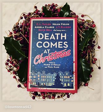 photograph of a copy of Death Comes at Christmas, edited by Marie O'Regan and Paul Kane, on a wreath of holly leaves and red berries, against a cream background