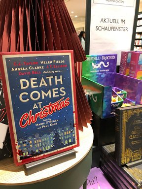 photograph of a bookstore display featuring Death Comes at Christmas, edited by Marie O'Regan and Paul Kane, standing in front of a red paper Christmas tree