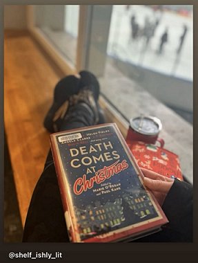 photograph of someone dressed in black trousers and trainers, sitting on a window seat, holding a copy of Death Comes at Christmas, edited by Marie O'Regan and Paul Kane