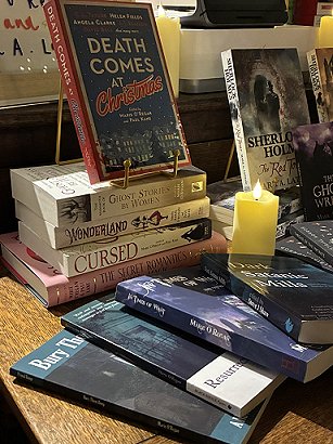 Book display featuring, at the back, Death Comes at Christmas, The Mammoth Book of Ghost Stories by Women, Wonderland, Cursed, and The Secret Romantic's Book of Magic, and at the front - Bury Them Deep, Resurrection Blues, In Times of Want and Dark Satanic Mills