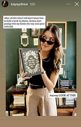 photograph showing Kelly Andrew in a green room, in front of a wooden desk piled high with books. She's wearing sunglasses and holding up a copy of The Secret Romantic's Book of Magic, edited by Marie O'Regan and Paul Kane, to show the black cover inside the dustjacket. Text on the cover reads: ONLY TRUE LOVE'S KISS WILL BREAK THE SPELL...